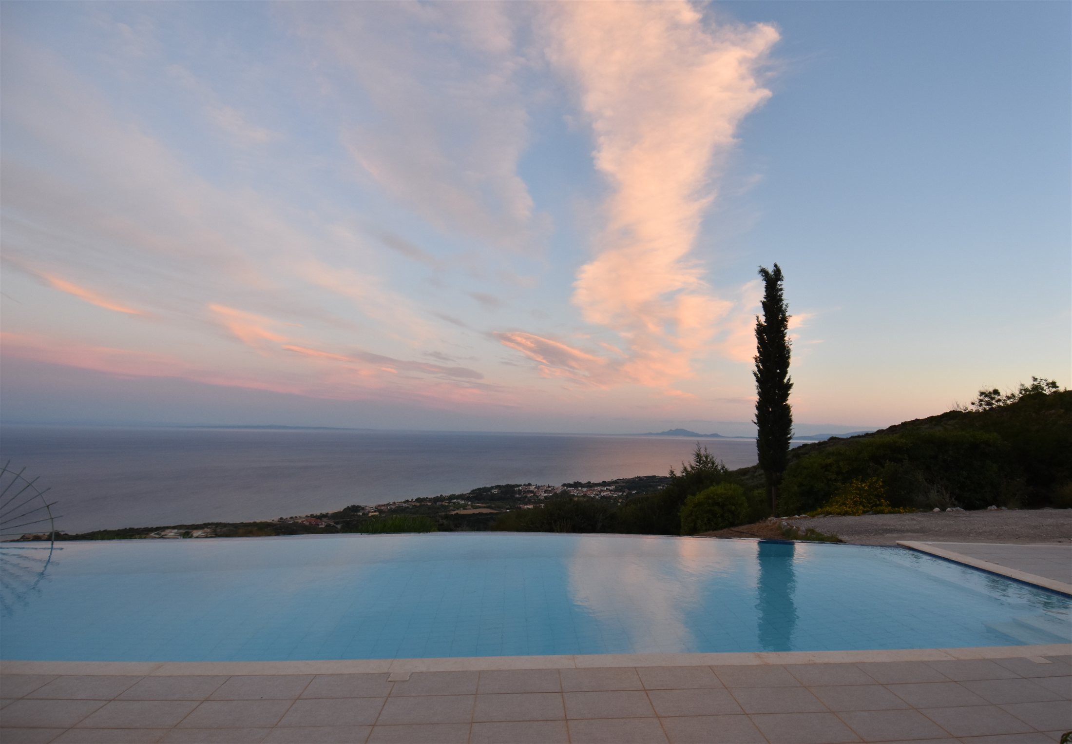Soft evening clouds above the infinity pool, with the Ionian Sea stretching towards the horizon
